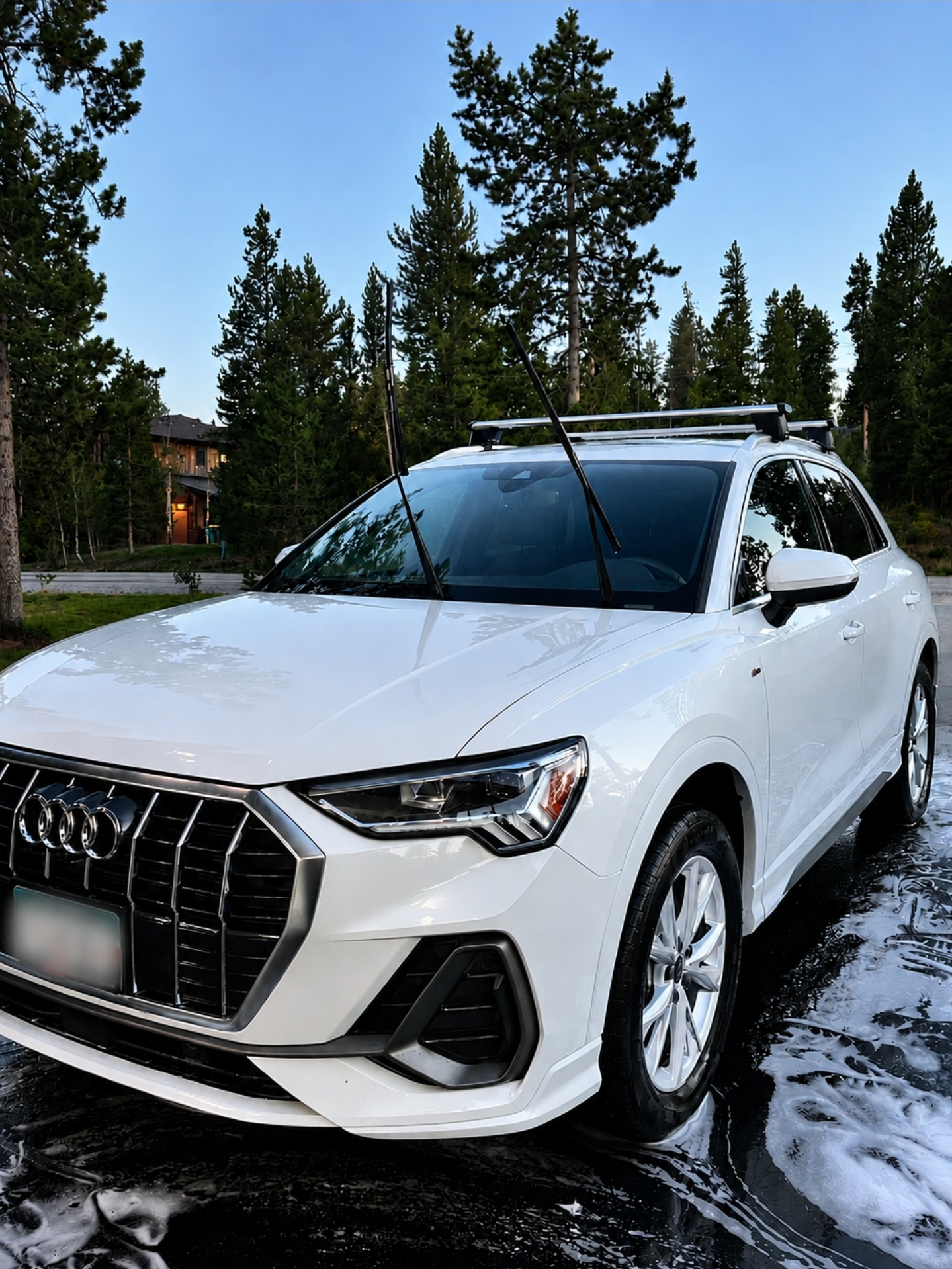 Black SUV being pressure washed with foam in a mountain driveway